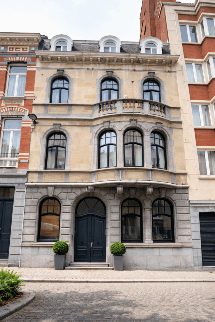 Maison de maître bruxelloise avec châssis en bois foncé et porte cintrée à double battant