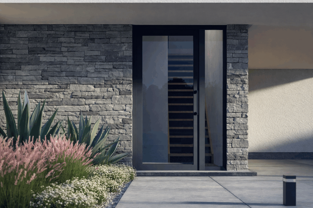 Porte d'entrée vitrée anthracite encastrée dans un parement en pierre naturelle