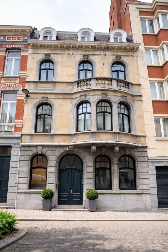 Maison de maître bruxelloise avec châssis en bois foncé et porte cintrée à double battant