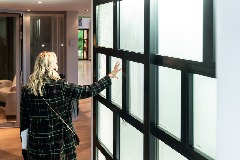 Cliente examinant un mur d'échantillons de vitrages dans le showroom Abihome
