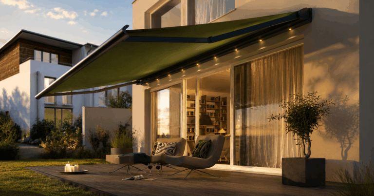 Store banne rétractable vert au-dessus d'une terrasse, éclairage LED intégré, salon extérieur et baies vitrées coulissantes en soirée.