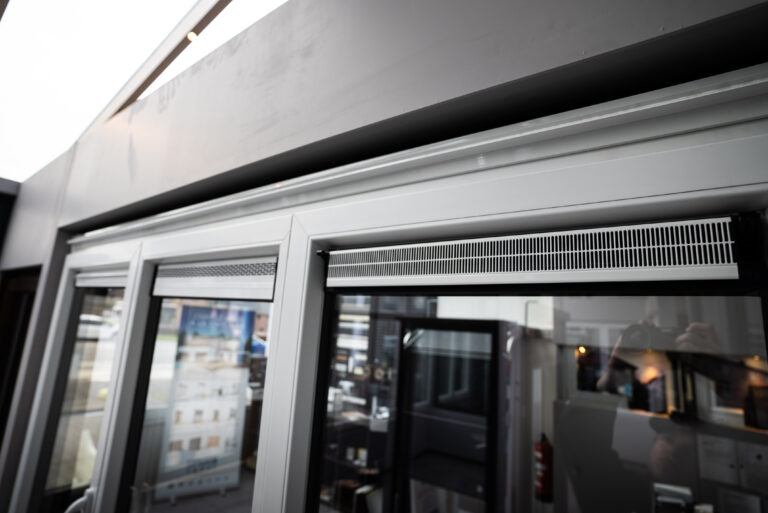 Détail des grilles de ventilation intégrées dans l'encadrement d'une véranda ou d'un châssis.