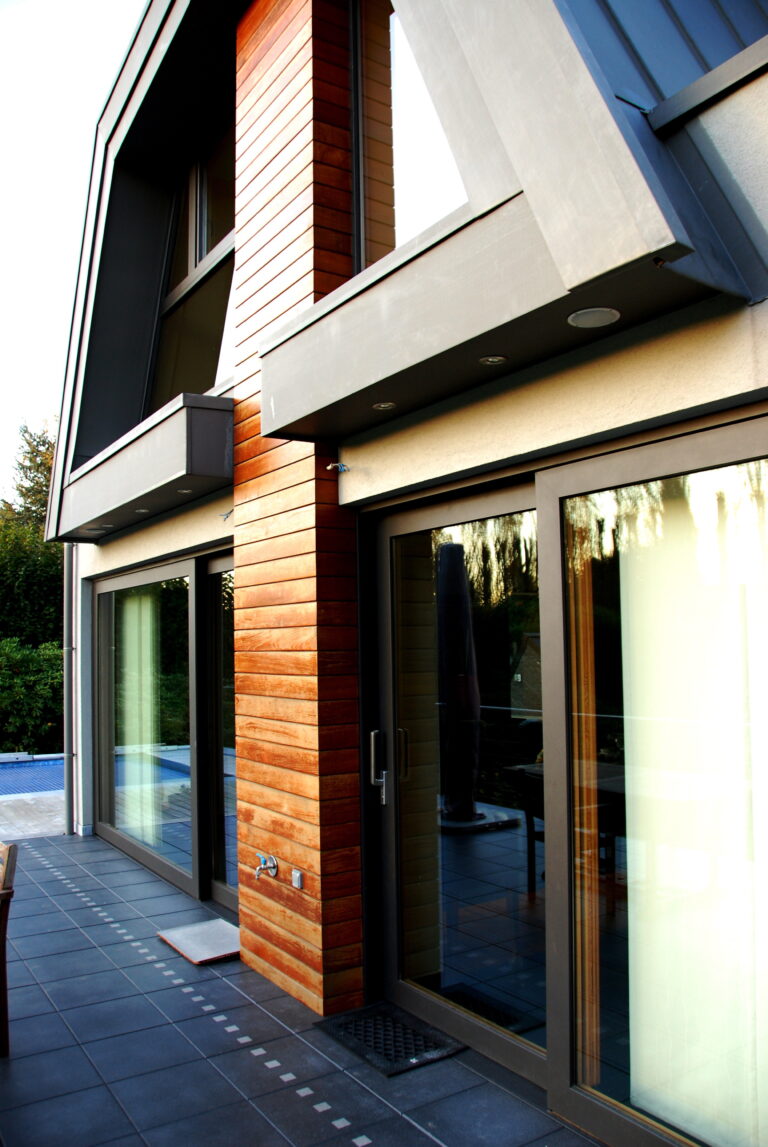 Maison contemporaine au bardage bois avec châssis coulissants en bois, piscine et terrasse.