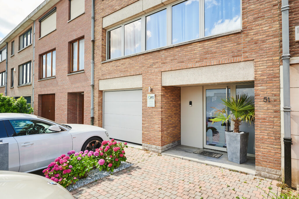 Châssis et porte d'entrée en aluminium blanc sur une maison en briques rouges