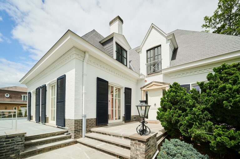 Villa blanche de style classique avec châssis en bois blanc et volets battants noirs