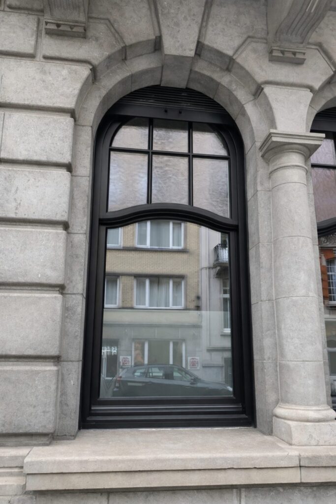 Black arched glazing-bar window in a round-arched ashlar opening