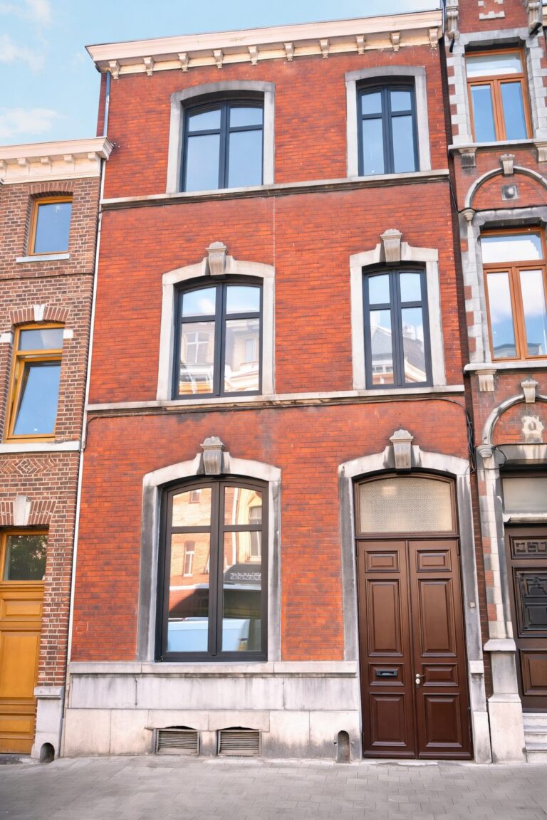 Woning in rode baksteen met gebogen pvc-ramen in donkerblauw en houten deur, in Ans