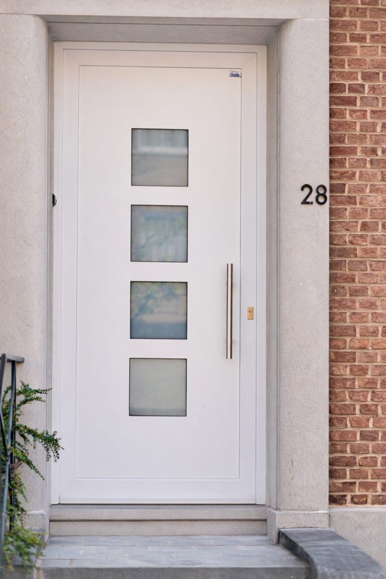 Porte d'entrée en PVC blanc à quatre vitrages carrés et barre de tirage inox