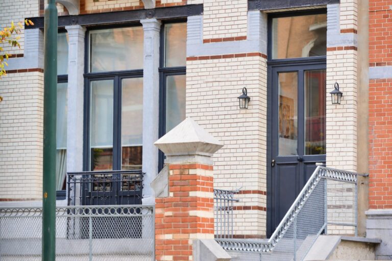 Châssis et porte d'entrée en bois bleu nuit sur une façade en briques claires à Uccle